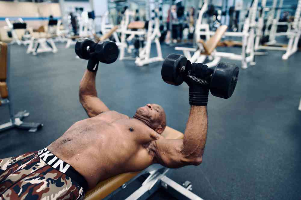 Using dumbells allows you to control how you exercise each arm. Man doing bench press using dumbells