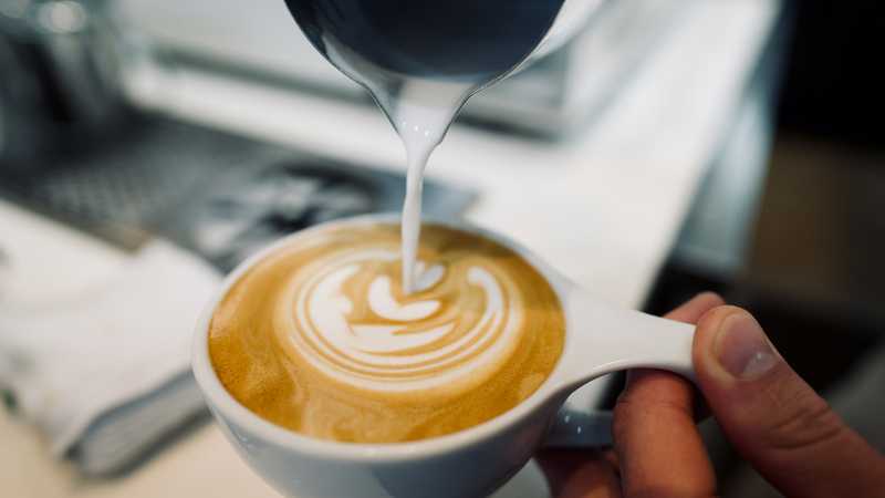 Barista pouring milk into a latte