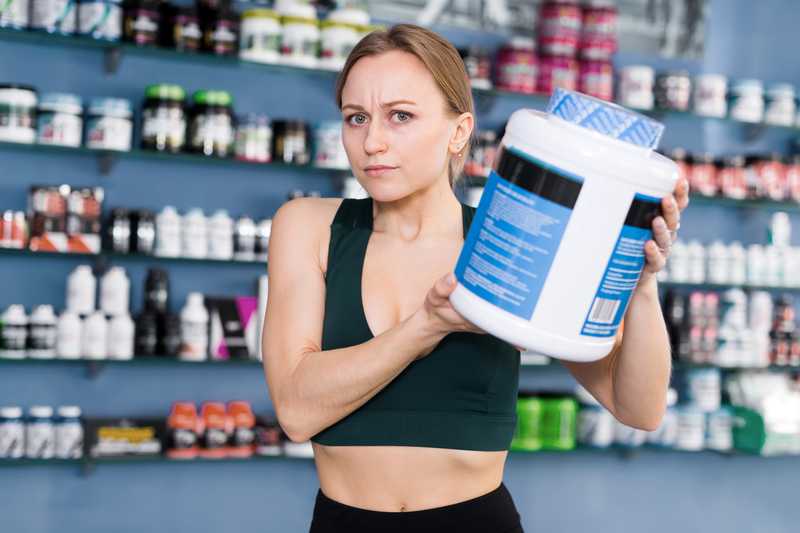 Woman holding big container of protein powder