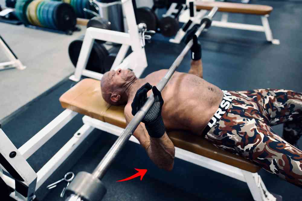 Make sure your elbows are positioned at about a 45-degree angle. Man doing bench press with elbows at 45 degrees