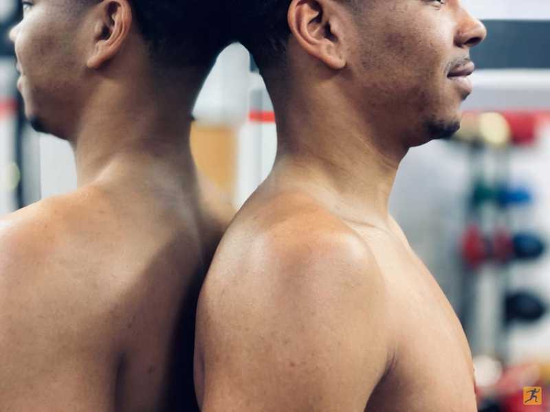 Man standing up straight against a mirror