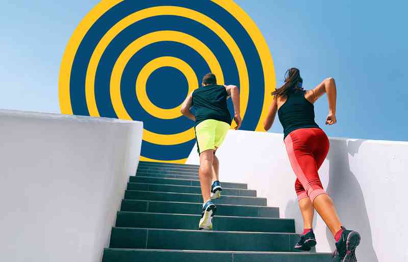 Man and woman running up stairs towards a large target